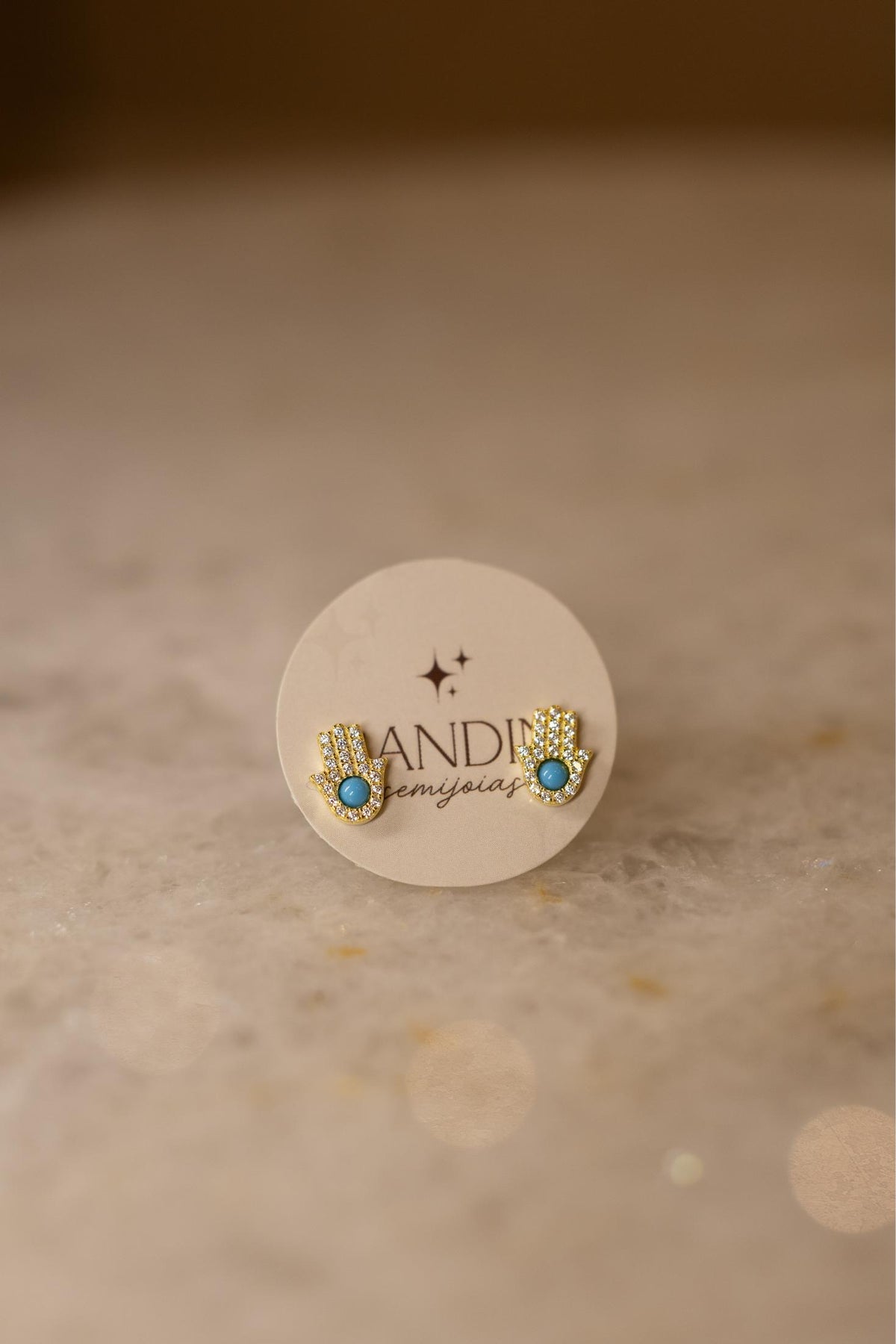 Brinco Mão de Hamsá Cravejada Turquesa Dourado